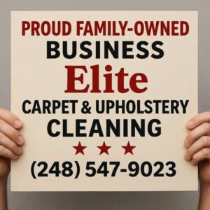 Owner of Elite Carpet & Upholstery Cleaning holding a proud family-owned business sign in Michigan